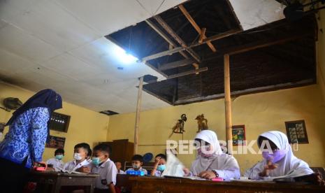 Siswa belajar di dalam ruangan kelas yang plafonnya rusak di Sekolah Dasar Negeri (SDN) 2 Klaling, Jekulo, Kudus, Jawa Tengah, Senin (17/1/2022). Kegiatan belajar-mengajar di sekolah tersebut tetap berjalan meskipun kondisi sebagian rung kelas rusak dan dapat membahayan siswa dan guru. Kudus Masih Izinkan Sekolah Gelar Pembelajaran Tatap Muka