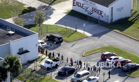 Siswa dievakuasi oleh polisi dari Marjory Stoneman Douglas High School di Parkland, Florida, pada hari Rabu (14/2), setelah seorang penembak melepaskan tembakan ke kampus.