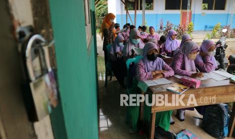 Siswa kelas 6 terpaksa belajar di teras sekolah Madrasah Ibtidaiyah (MI) Roudlotul Muttaqin Desa Penompo, Jetis, Kabupaten Mojokerto, Jawa Timur, Kamis (18/11/2021). Mereka sudah satu pekan belajar di teras sekolah karena atap bangunan kelas sekolahnya ambruk akibat hujan disertai angin kencang. 