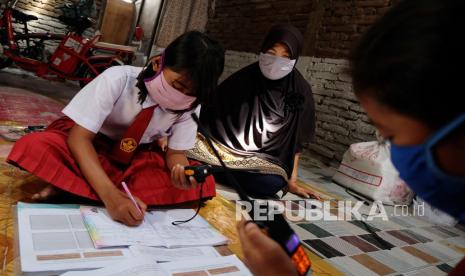 Siswa kelas VI SD Negeri Mojo, Safira (kiri) dan Diva (kanan) menggunakan Handy Talky (HT) saat menyimak materi pelajaran guru pada pembelajaran jarak jauh dari rumahnya di Kampung Semanggi, Solo Jawa Tengah, Selasa (29/9/2020). Pihak sekolah menyediakan fasilitas HT untuk komunikasi dua arah siswa dan guru, guna mendukung pembelajaran jarak jauh saat pandemi COVID-19. 