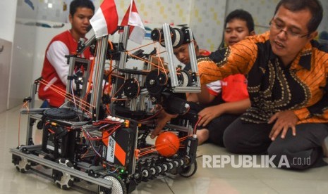 Siswa Madrasah Aliyah TechnoNatura yang tergabung dalam tim Never Before bersama Kepala Sekolah Tras Rustamaji (kanan) mempraktikkan kinerja robot WowWi karya mereka di Kelapa Dua, Depok, Jawa Barat, Kamis (3/8). 