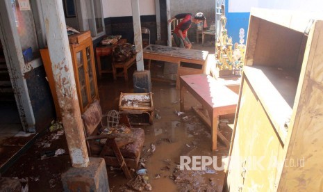 Siswa melintasi halaman kelas yang dipenuhi lumpur dan barang-barang sekolah di SMP PGRI Haurpugur, Desa Haurpugur, Kecamatan Rancaekek, Kabupaten Bandung, Senin (18/4). 