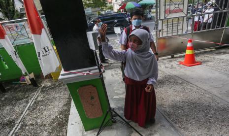 Siswa mengecek suhu tubuh saat akan mengikuti Pembelajaran Tatap Muka (PTM) di Madrasah Ibtidaiyah Negeri 1 Langkai, Palangkaraya, Kalimantan Tengah, Selasa (8/2/2022). Pemkot Palangkaraya memberlakukan PTM dengan sistem penyesuaian zonasi kelurahan penyebaran COVID-19, seperti PTM 100 persen bagi wilayah yang berada di zona hijau dan 50 persen di zona oranye serta pembelajaran secara daring untuk kawasan zona merah COVID-19.