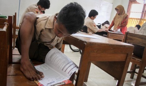 Siswa penyandang disabilitas, Muhammad Salwa mengerjakan soal ujian nasional (UN) Bahasa Inggris menggunakan kakinya di SLB-D YPAC, Solo, Jawa Tengah, Kamis (4/5). 