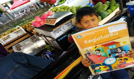 Siswa SD Cigugur Tengah Mandiri 1 Cimahi, , Gilang (7) mengerjakan tugas sekolahnya di mobil pickup tempat ibunya berjualan buah-buahan di Bandung, Jumat (16/10).