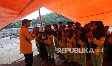 Siswa SDN Jugosari 3 belajar di tenda di pinggir Sungai Regoyo, Desa Jugosari, Candipuro, Lumajang, Jawa Timur, Jumat (7/1/2022). Pasca terisolirnya siswa SDN Jugosari 3 tersebut sejumlah guru terpaksa melakukan kegiatan belajar mengajar di tenda darurat selama aliran Sungai Regoyo tidak dibanjiri lahar Gunung Semeru. 