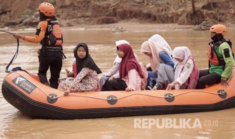 Tim Water Rescue DMC (Disaster Management Centre) Dompet Dhuafa membantu siswa SDN 1 Sajira, Kabupaten Lebak, menyeberangi Sungai Ciberang untuk menuju sekolahnya. 