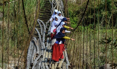 Siswa Sekolah Dasar (SD) menyeberangi Jembatan Gantung Lengkongjaya yang melintasi Sungai Ciwulan, Desa Pusparaja, Kabupaten Tasikmalaya, Jawa Barat, Selasa (23/7/2019). 