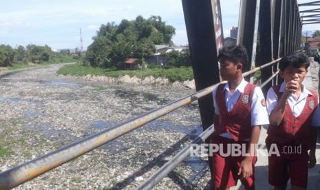 Siswa Sekolah Dasar tengah berjalan kaki di jembatan Citarum lama, Senin (19/2). Kondisi sungai Citarum lama yang tidak aktif dipenuhi dengan sampah dan air limbah pabrik.