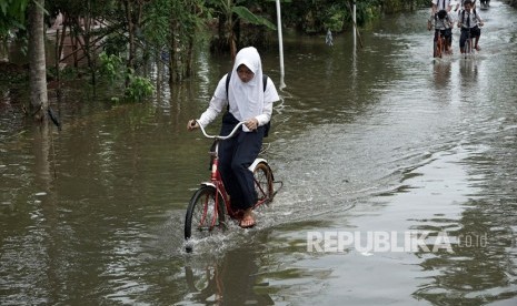 Siswa sekolah melintasi genangan air akibat banjir di Desa Kedungbenda, Nusawungu, Cilacap, Jateng, Selasa (13/11/2018). 