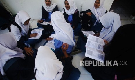 Siswa Sekolah Menegah Kejuruan Negeri (SMKN) 3 Depok mengulang pelajaran di teras kelas saat menunggu Ujian Nasional Berbasis Komputer (UNBK) sesi satu selesai di Sukmajaya Depok, Jawa Barat, Senin (25/3/19). 