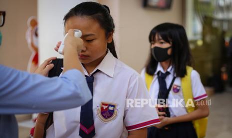 Siswa sekolah menjalani pemeriksaan suhu tubuh sebelum memasuki lingkungan sekolah di Jakarta Nanyang School, Tangerang, Banten, Rabu (4/3/2020). Ada sekolah yang melarang muridnya salaman dengan guru agar tak tertular corona.