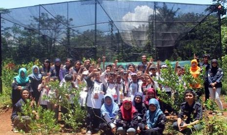 Siswa-siswi SDN Taman Pagelaran berfoto dengan anggota Himakova di depan kandang display di penangkaran kupu-kupu 'Sarpedon'.