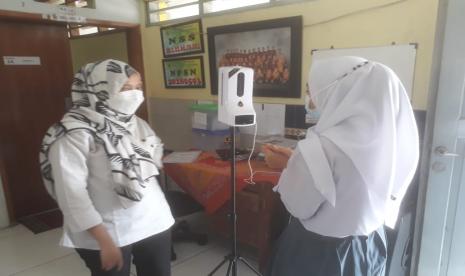 Siswa SMA SLB di Kota Bandung tengah mengecek kondisi suhu tubuh didampingi oleh petugas sekolah, Rabu (15/9).