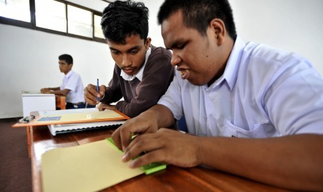 Siswa tuna netra didampingi pendampingnya menjawat pertanyaan saat mengikuti Ujian Nasional (UN) tingkat SMP di SLBA Yapti Makassar, Sulawesi Selatan, Senin (9/5).