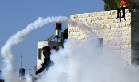 Smoke from a tear gas canister fired by Israeli security officers (unseen) rises in front of stone-throwing Palestinians. West Bank has seen mounting clashes between Israeli soldiers and Palestinian protestors, leaving two Palestinians dead since the launch on Nov. 14 of an eight-day Israeli offensive in the Gaza Strip.