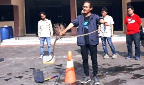 Snake handler dari Yayasan Ular Indonesia Sioux, Muhammad Dzawil Arham, menunjukkan cara aman mengevakuasi ular dari rumah. 