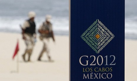 Soldiers walk near a sign of the G20 summit on a beach in Los Cabos June 17, 2012. G20 leaders will kick off two days of meetings in the Pacific resort of Los Cabos on Monday.   