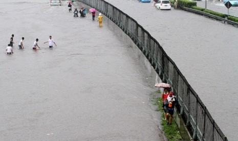 Some people trapped by flood try to cross the road near a toll road in Jakarta on Thursday. (illustration)