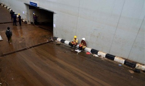 Some rescue team members rest during car evacuation from basement of Plaza UOB in Jakarta on Tuesday. The evacuation process sometimes is hampered by mud and strong smell from the basement.