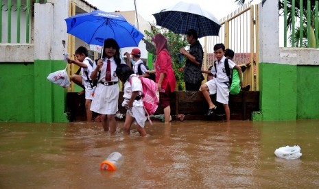 Some school children walk through flooded street to reach their school in East Jakarta. (illustration)