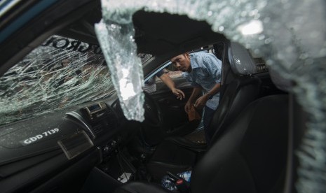 Sopir taksi melihat kendaraannya yang dirusak oleh pengemudi ojek berbasis online di jalan Rasuna Said, Jakarta, Selasa (22/3).