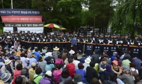 South Korean policemen stand guard in front of the main gate of the Evangelical Baptist Church premises, as church believers sit in front of the police barricade, in Anseong June 11, 2014.