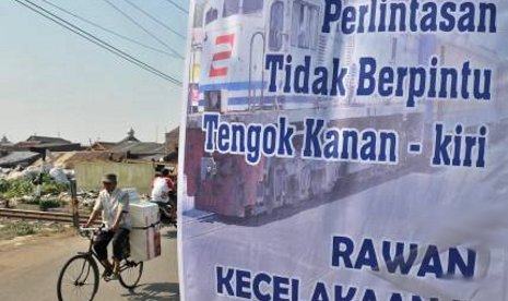 Spanduk PT KAI memperingatkan masyarakat terhadap perlintasan kereta api yang tidak dijaga dan tak memiliki palang pintu.