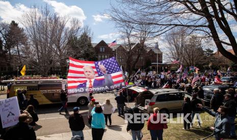 Spanduk raksasa yang menggambarkan Presiden Trump pada dibawa ke depan kediaman Gubernur saat demonstrasi Liberate Minnesota di St. Paul, Minn, Jumat (17/4). Semakin banyak protes yang dipentaskan di seluruh Amerika Serikat untuk menentang peraturan yang menganjurkan dirumah saja saat masa pandemic virus Corona. 