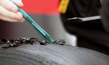 Staf Pirelli tengah memeriksa ban pecah dari salah satu kendaraan tim Formula 1.