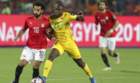 Stiker timnas Mesir, Mohamed Salah (kiri) dikawal oleh bek Zimbabwe, Nyasha Mushekwi pada laga Piala Afrika 2019, Sabtu (22/6). 