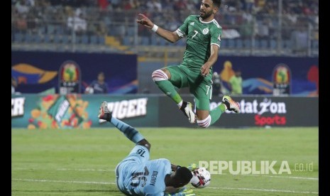 Striker Aljazair Riyad Mahrez melompati kiper Senegal Edouard Osoque Mendy  pada pertandingan Grup C Piala African antara Aljazair dan Senegal di Kairo, Jumat (28/6). 