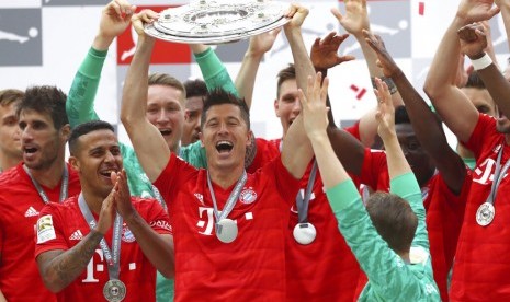 Striker Bayern Muenchen, Robert Lewandowski (tengah) mengangkat trofi Bundesliga musim 2018/2019.