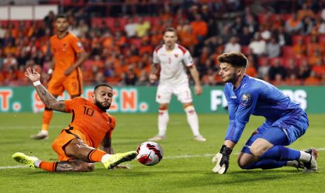 Striker Belanda, Memphis Depay (kiri), berusaha menerjang bola di depan penjaga gawang Montenegro, Matija Sarkic, ketika kedua tim bertanding di Eindhoven, Ahad (5/9).