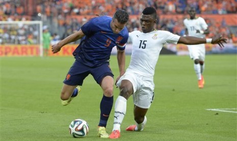 Striker Belanda, Robin Van Persie, tengah memperebutkan bola dengan pemain Ghana, Sumaila Rashid, pada sebuah laga uji coba jelang Piala Dunia 2014.