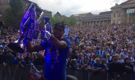 Striker Huddersfield Town, Nahki Wells memegang trofi playoff Divisi Championship dengan latar suporter tim, di Kota Yoskshire, Selasa (30/5).