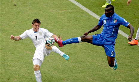 Striker Italia Mario Balotelli (kanan) saat berduel dengan pemain Uruguay Cristian Rodriguez 