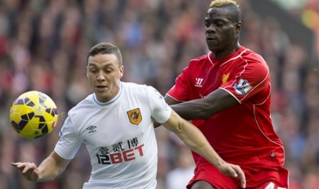 Striker Liverpool Mario Balotelli (kanan) berduel bola dengan pemain Hull City dalam pertandingan Liga Primer Inggris di Anfield, Sabtu (25/10).