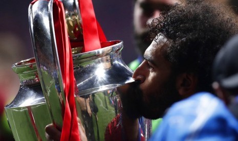 Striker Liverpool, Mohamed Salah mencium trofi Liga Champions.