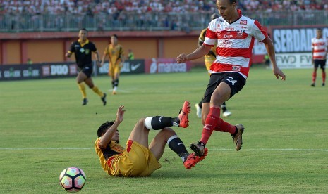 Striker Madura United (MU) FC Peter Odemwingie (kanan) melewati hadangan pesepak bola Mitra Kukukar, Dhika Pratama Putra (kiri bawah) dalam lagaLiga 1 di Stadion Gelora Ratu Pamelingan (SGRP) Pamekasan, Jumat (28/4). Melawan PS TNI, Madura United akan menggunakan Stadion Gelora Bangkalan.