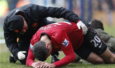 Striker Manchester United, Robin Van Persie (kanan), mengalami cedera saat menghadapi Queens Park Rangers di laga Liga Primer Inggris di Loftus Road,London, Sabtu (23/2). 