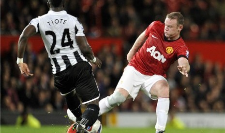 Striker Manchester United, Wayne Rooney (kanan), mendapat tackle dari  pemain Newcastle United, Cheick Tiote, dalam laga putaran ketiga Piala Liga Inggris di Stadion Old Trafford, Manchester, Rabu (26/9). 