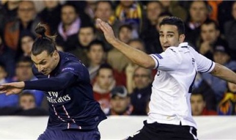 Striker Paris Saint-Germain, Zlatan Ibrahimovic (kiri), berduel dengan pemain Valencia, Adil Rami, di leg pertama babak 16 besar Liga Champions di Stadion Mestalla, Valencia, Selasa (12/2).  