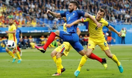 Striker Prancis Olivier Giroud (biru) dijaga pemain Rumania Vlad Chiriches.