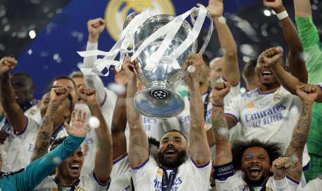 Striker Real Madrid, Karim Benzema (tengah), mengangkat trofi saat melakukan selebrasi bersama rekan setim usai mengalahkan Liverpool 1-0 di partai final Liga Champions di Stade de France, Paris, pada Ahad (29/5/2022) dini hari WIB.