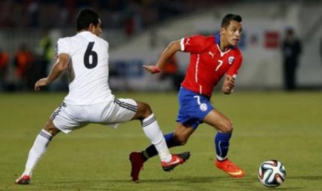 Striker timnas Cile, Alexis Sanchez (kanan), berebut bola dengan pemain timnas Mesir, Ramy Rabia, dalam laga uji coba di Santiago, Cile, Jumat (30/5). 