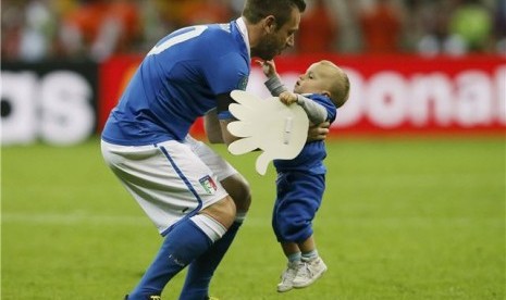 Striker timnas Italia, Antonio Cassano, menggendong anaknya usai Italia mengalahkan Jerman di babak semifinal Piala Eropa 2012. 