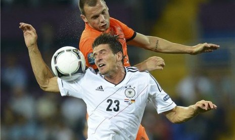 Striker timnas Jerman, Mario Gomez (depan), terlibat duel udara dengan pemain Belanda, John Heitinga, di laga Grup B Piala Eropa 2012 di Kharkiv, Ukraina, pada Rabu (13/6). 