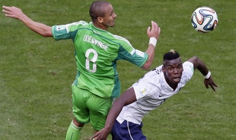 Striker timnas Nigeria, Peter Odemwingie (kiri) berebut bola dengan Paul Pogba pada laga Piala Dunia 2014. Odemwingie tengah diincar Madura United. 