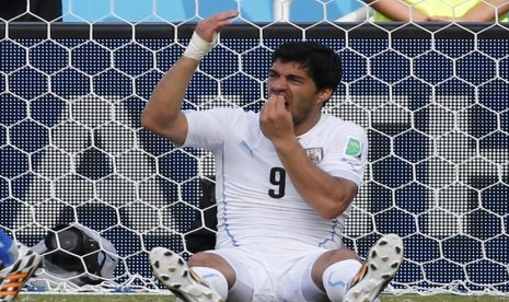 Striker Timnas Uruguay, Luis Suarez, memegangi giginya usai terlihat menggigit pemain Italia, Giorgio Chiellini, di laga terakhir Grup D Piala Dunia 2014 Brasil di Arena Dunas, Natal, Selasa (24/6).